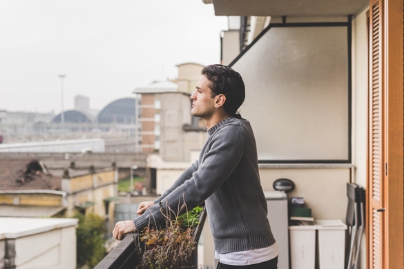 Half length of young handsome Aquarius man standing on a balcony outdoor