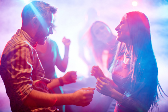 Happy young couple dancing in night club