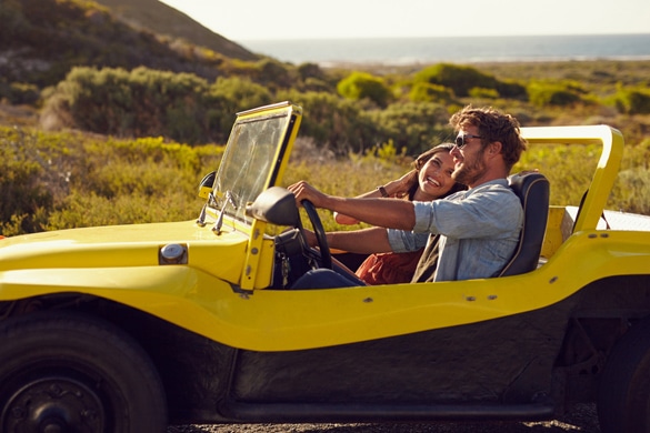 Young man with his girlfriend on road trip in a open top car