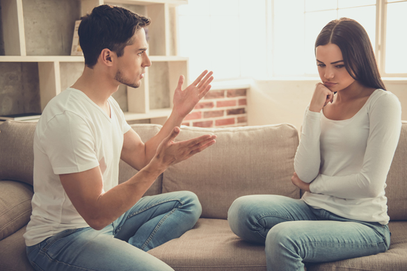 Beautiful young couple is having a quarrel while sitting on sofa at home - How to tell when an Aquarius man is done with you