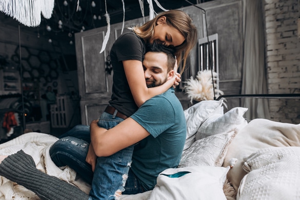 Loving couple hug each other on the bed - How Does An Aquarius Man Fall In Love